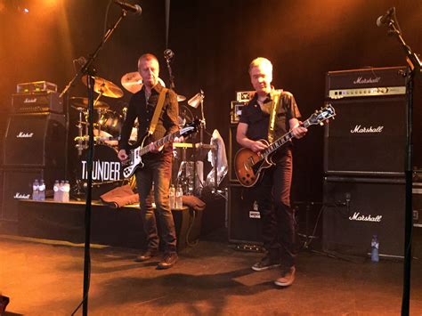 two men playing guitars on stage with microphones in the foreground and ...