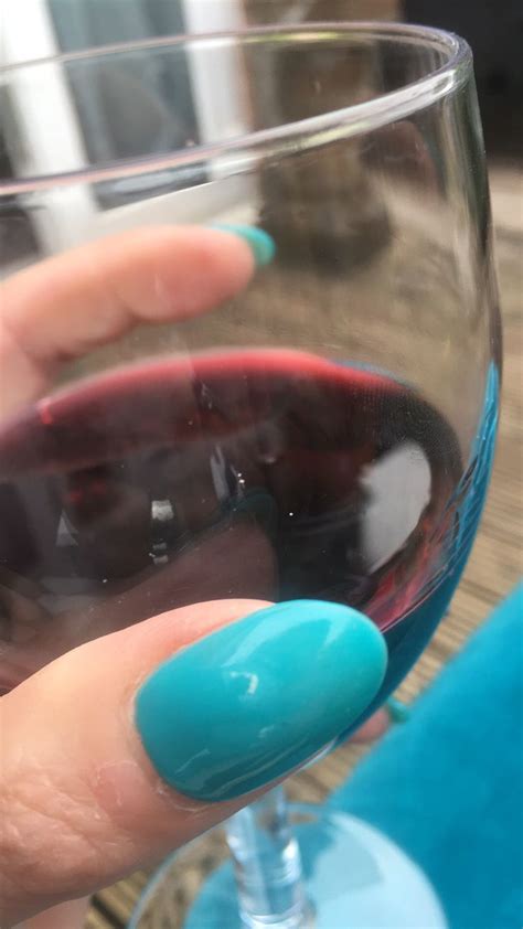 a woman's hand holding a wine glass with red and blue liquid in it