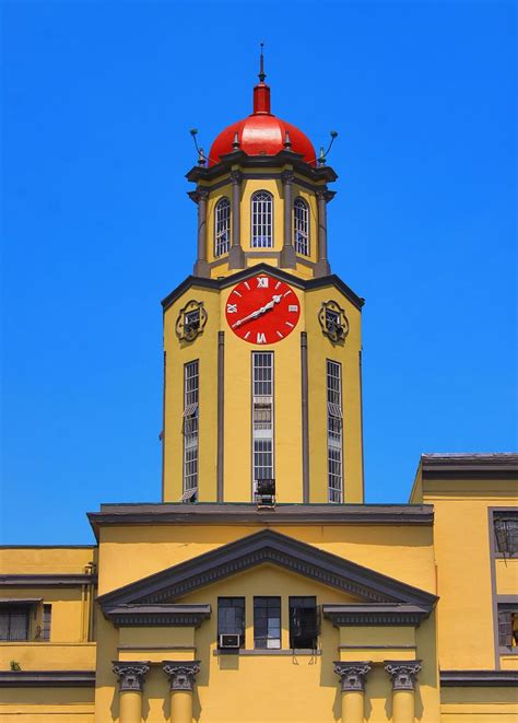 a large yellow building with a red clock on it