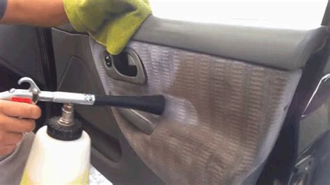 a person cleaning the inside of a car with a spray bottle and sponge on it
