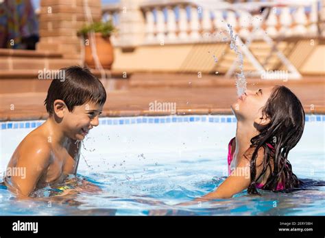 Two friends spitting water from mouth in a pool Stock Photo - Alamy