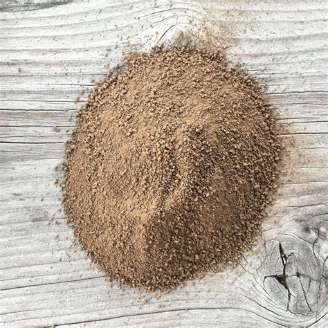 a pile of dirt sitting on top of a wooden table next to a piece of wood