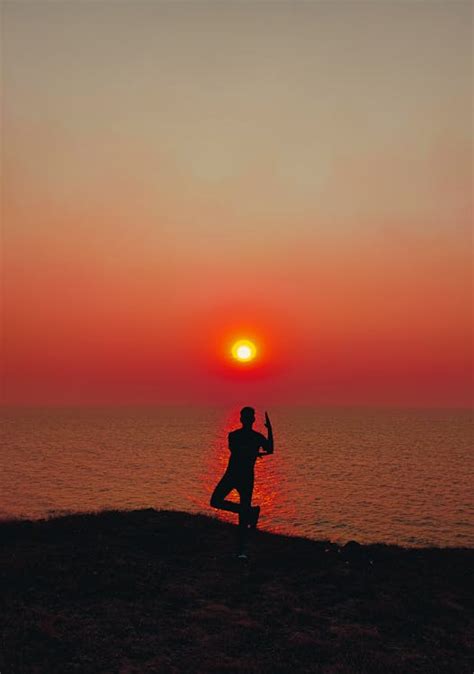 Silhouette of a Person on a Cliff Posing During Sunset · Free Stock Photo