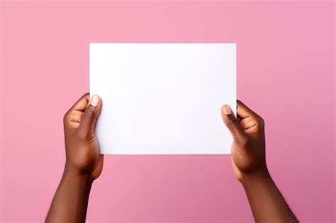 Premium AI Image | A human hand holding a blank sheet of white paper or card isolated on pink ...