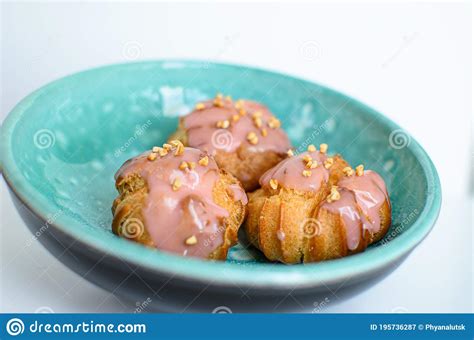 Three Delicious Homemade French Profiteroles With Pieces Of Nuts And Strawberry Cream On Blue ...