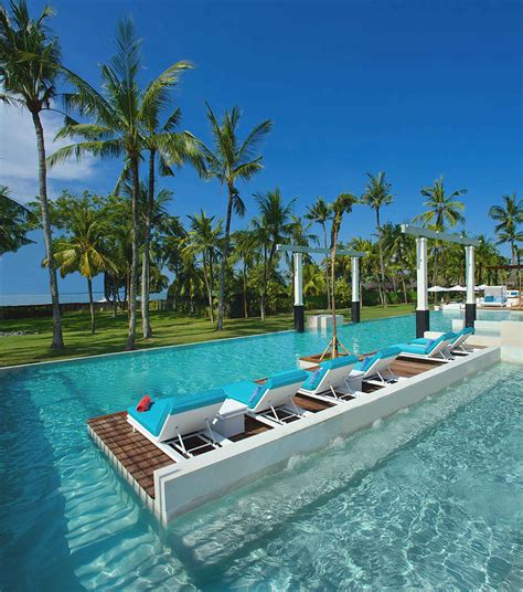 an outdoor swimming pool with lounge chairs and palm trees in the ...