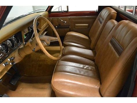 the interior of an old car with brown leather seats and steering wheel, showing the dashboard