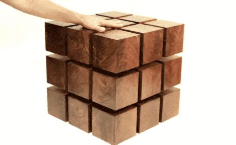 a hand reaching for a block of wood that is stacked on top of each other