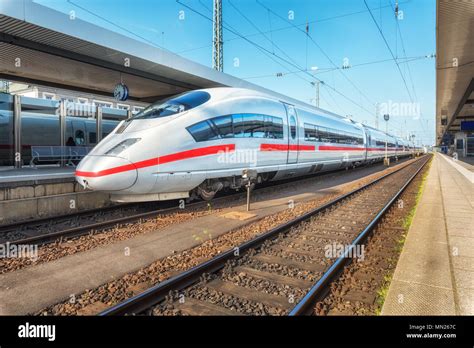 High speed white train on the railway station at sunset. Nuremberg, Germany. Modern intercity ...