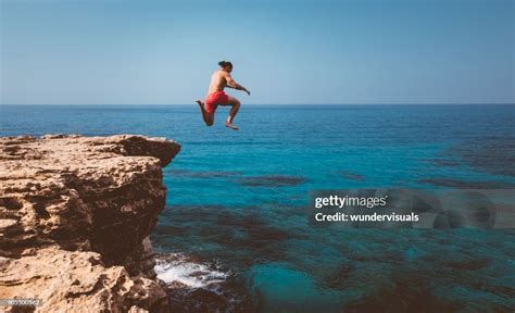 Young Adventurous Diver Jumping Off Cliff Into Ocean High-Res Stock ...