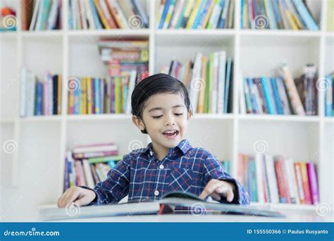 Cute Little Boy Reading a Book in the Library Stock Photo - Image of kids, elementary: 155550366