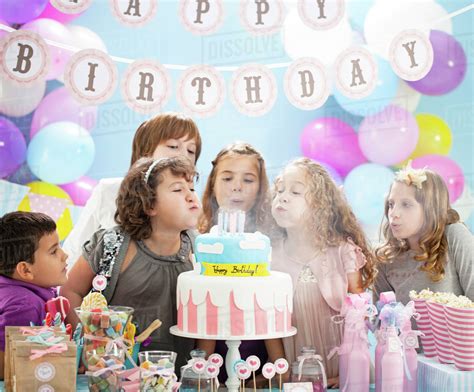 Children blowing out candles on birthday cake in party - Stock Photo - Dissolve