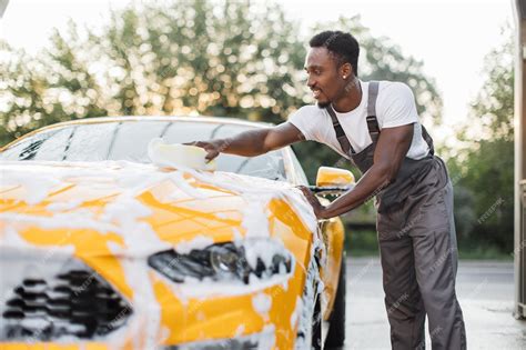 Premium Photo | Car hood cleaning with yellow sponge and soap foam outdoors at car wash service