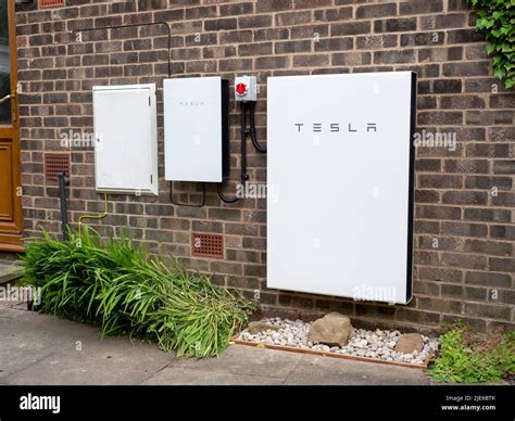 Tesla Powerwall 2 and Backup Gateway 2 battery storage system installed on a brick house wall ...