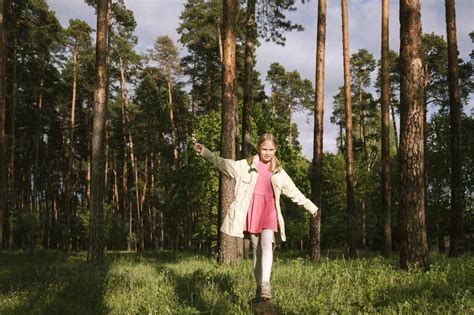 Girl walking on log in forest stock photo