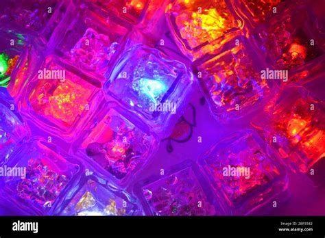 Many different colors of small plastic luminous ice cubes floating in water are located in ...
