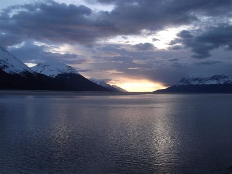 the sun is setting over some mountains and water