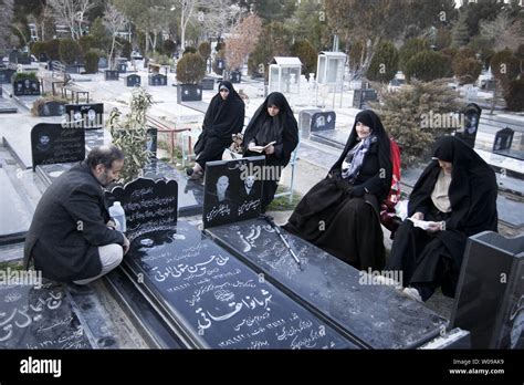 An Iranian family prays next to the graves of their loved ones at ...