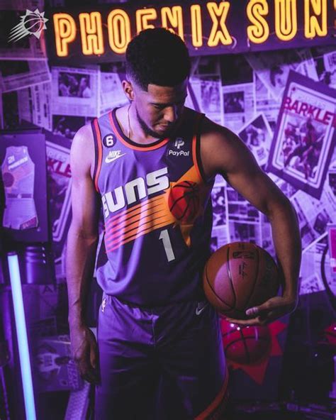 a man holding a basketball in front of a neon sign that reads phoenix suns