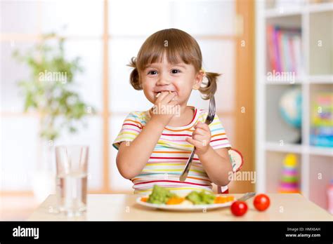 Funny little girl has a lunch in kindergarten Stock Photo - Alamy