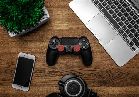 Silver Macbook Beside Black Sony Ps4 Dualshock 4, Silver Iphone 6, and Round Black Keychain on ...
