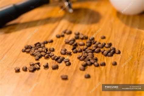 Coffee beans and portafilters placed on wooden table with empty cup in cafe — metallic, brew ...