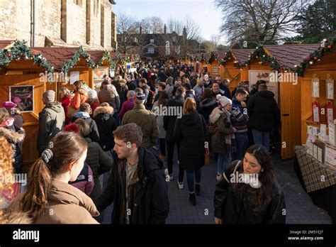 Christmas shoppers at Winchester Christmas market with wooden chalets next to the medieval ...