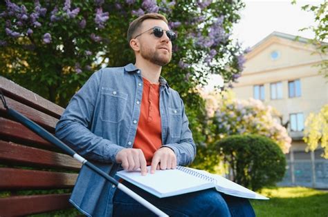 Premium Photo | Blind man reading braille book sitting on bench in summer park resting