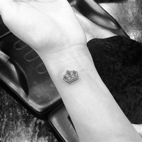 Small crown tattoo on the left wrist.