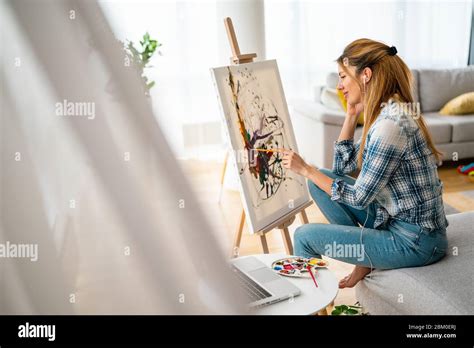 Beautiful woman painting on canvas at her home or workshop Stock Photo ...