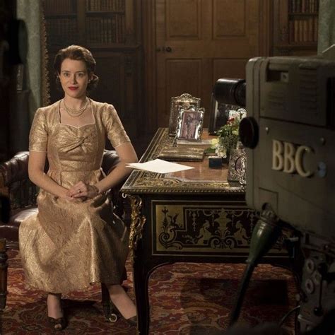 a woman sitting at a desk in front of a tv set with an old fashioned camera