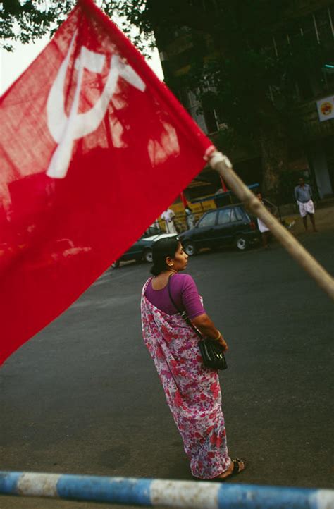 Stuart Freedman | India - Kerala - A woman walks past a Communist flag