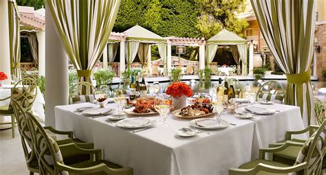 an outdoor dining area with white table cloths, green chairs and red ...