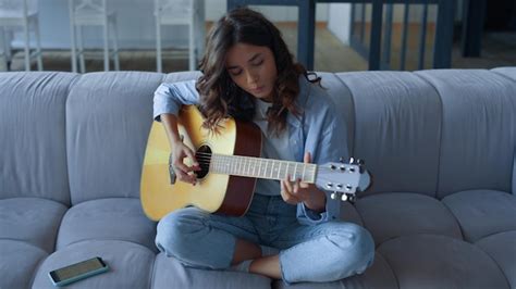 Premium Photo | Focused girl learning to play guitar at home young woman playing guitar