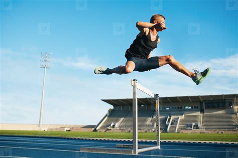 Professional sprinter jumping over a hurdle stock photo (123420) - YouWorkForThem