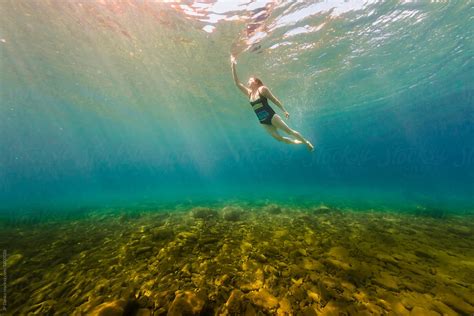 "Young Woman Swimming Underwater In Crystal Clear Summer Lake" by Stocksy Contributor "JP Danko ...