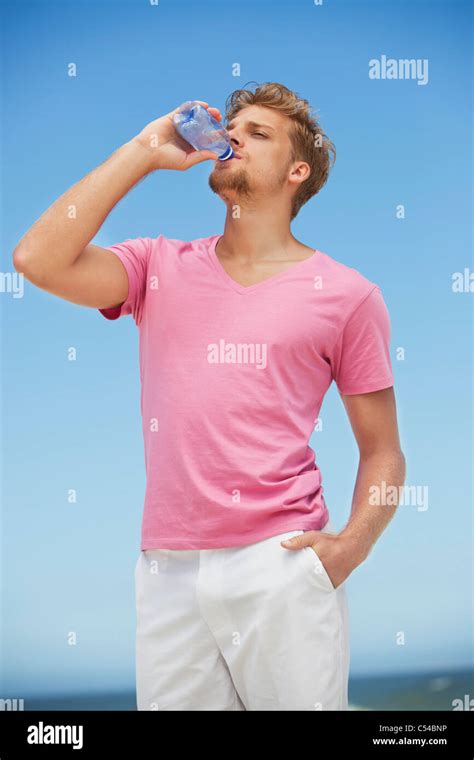 Young man drinking water from a water bottle on the beach Stock Photo ...