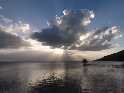 the sun is shining through clouds over water