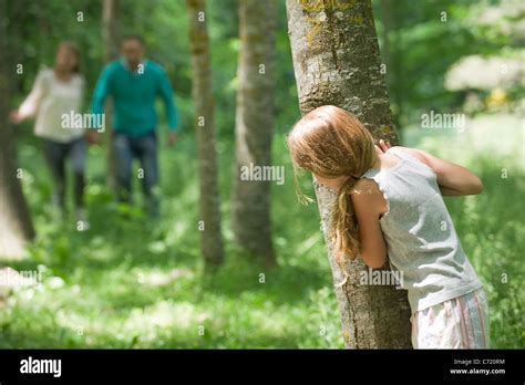 Girl hiding behind tree Stock Photo - Alamy