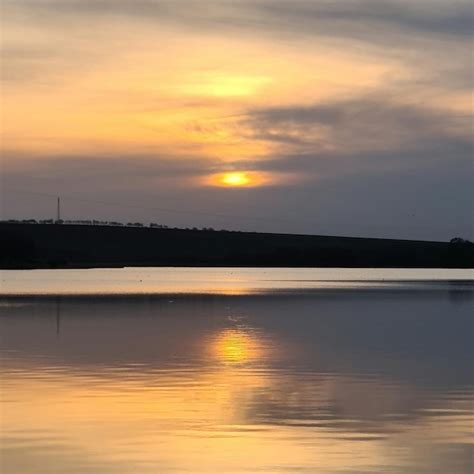 Premium Photo | A lake with a sunset and a hill in the background