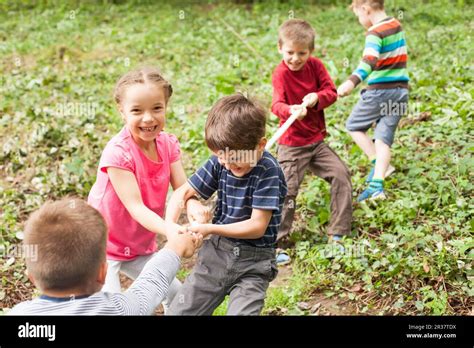 Group of happy smiling kids playing tug-of-war with rope in green park ...