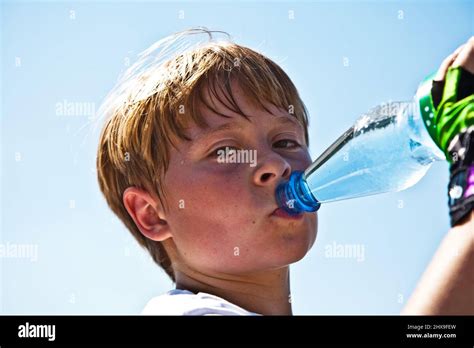 boy is sweating and thursty from doing sports and drinks mineral water out of a bottle Stock ...