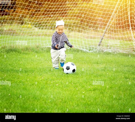 Little boy playing football on the field with gates Stock Photo - Alamy