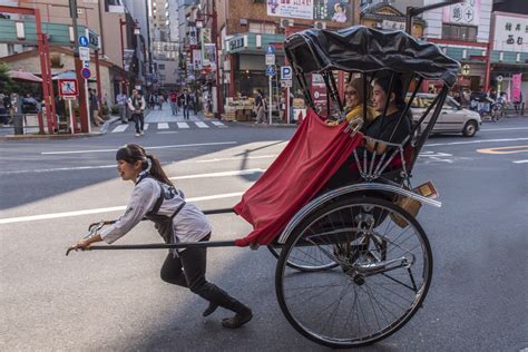 Two people touring on a rickshaw ("jinrikisha") pulling by a woman in ...