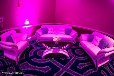 a living room filled with furniture and pink lighting on the wall behind it is a round coffee table