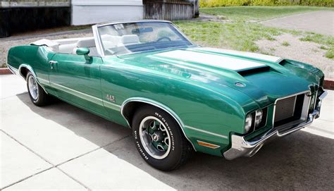 a green car is parked on the sidewalk