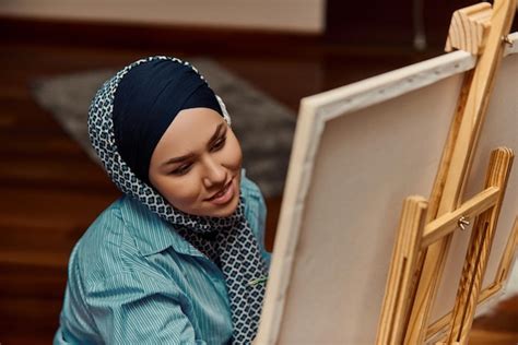 Premium Photo | A woman in a hijab paints on canvas with a brush and tempera