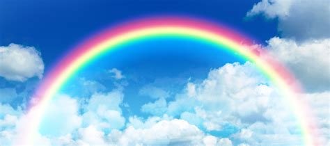 Composite image of rainbow against idyllic view of clouds against sky ...
