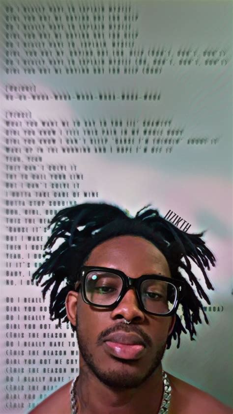 a man with glasses and dreadlocks in front of a computer code wallpaper