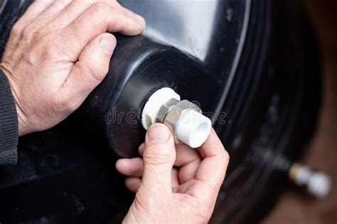 Plumber Screws an Adapter for a Polypropylene Pipe To a Water Tank. Installation of a Summer ...